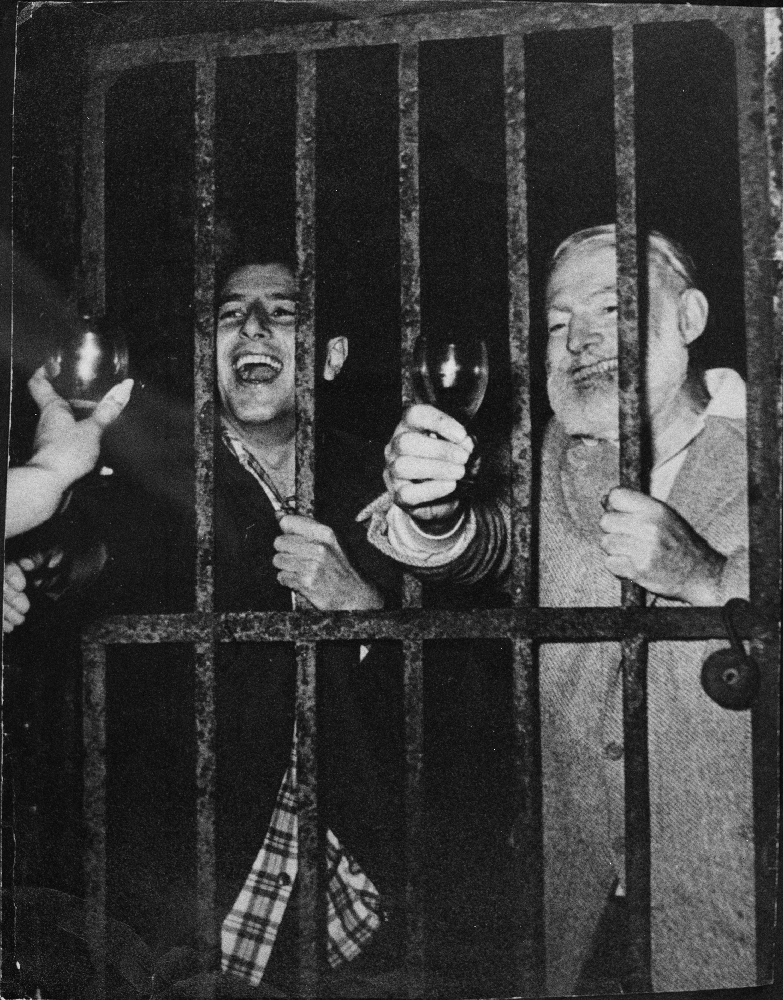 EH8969P August 1959 Ernest Hemingway and Antonio Ordonez behind bars drinking and laughing. Copyright unknown in the Ernest Hemingway Collection at the John F. Kennedy Presidential Library and Museum, Boston.